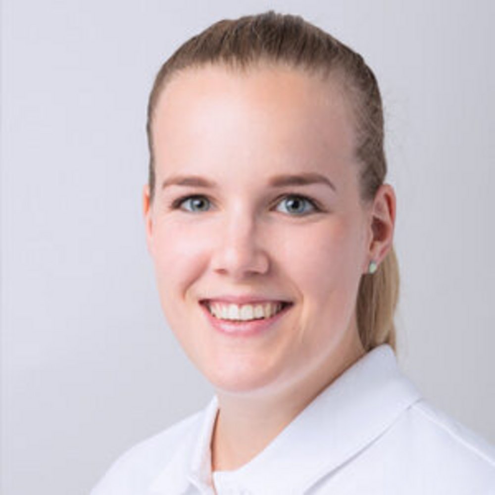 Portrait d’une jeune femme souriante portant un polo blanc.